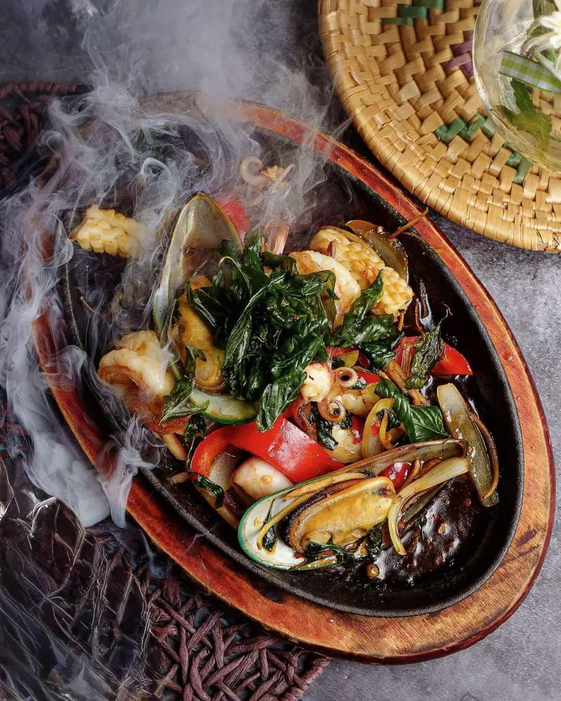 Sizzling seafood with basil and chilli on a hot plate, steam rising